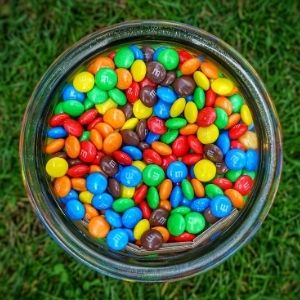 A jar of M&M's on a lawn