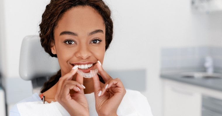Teen girl holding up an Invisalign clear aligner